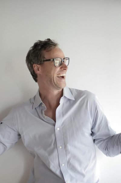Portrait Photo of Laughing Man in White Dress Shirt and Black Framed Eyeglasses Celebrating